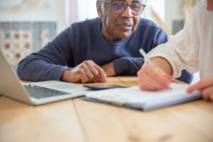people looking over paperwork with computer